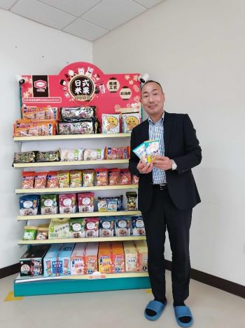 写真　商品を手にする田野信夫董事長・総経理（青島亀田提供）