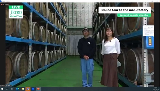 写真　貯蔵庫内で、樽貯蔵について説明する杜氏の高妻淑三（こうづまよしみ）氏（左）（ジェトロ撮影）